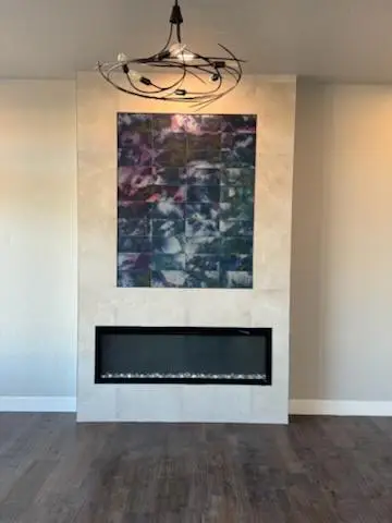 Modern living room featuring a stylish fireplace with glass stones, a large abstract artwork above, and a contemporary chandelier
